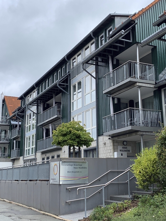 Eingangsbereich mit Treppe zu einem mehrstöckigen, modernen Gebäude der Ferienanlage Braunlage mit Balkonen.