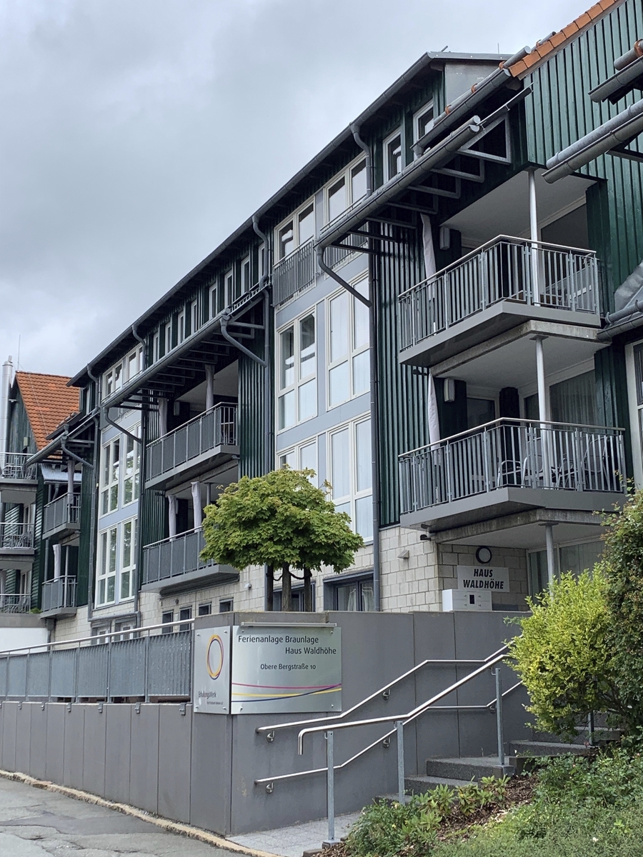 Eingangsbereich mit Treppe zu einem mehrstöckigen, modernen Gebäude der Ferienanlage Braunlage mit Balkonen.