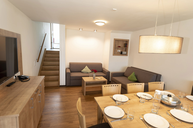 Wohnzimmer in einem Ferienhaus mit Esstisch und Sofas.