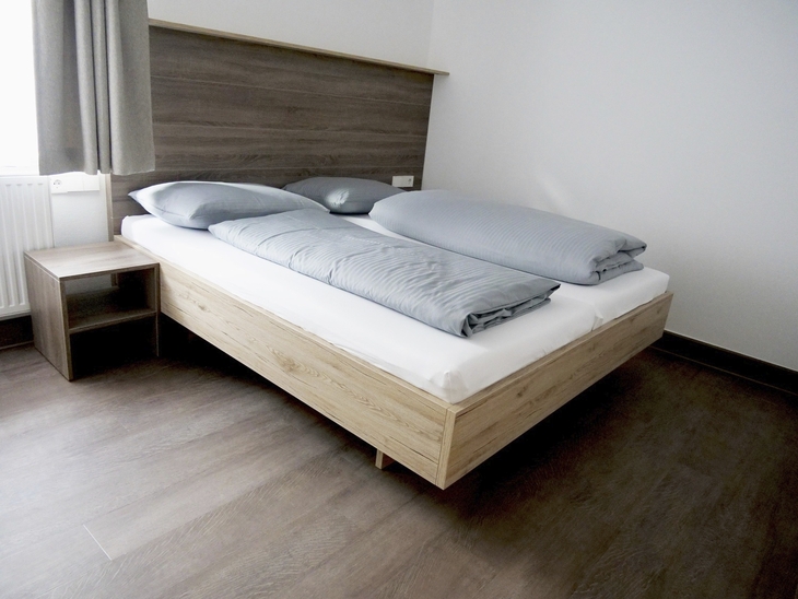 Modernes Schlafzimmer mit Doppelbett und grauer Bettwäsche.