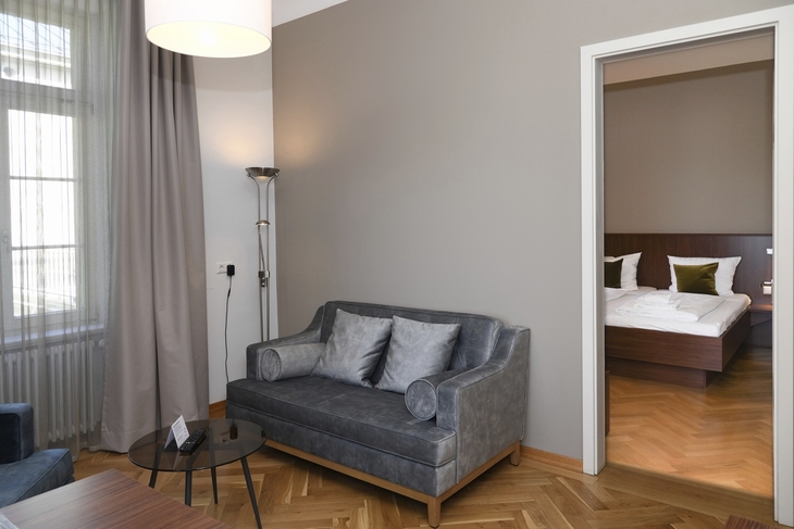 Wohnzimmer mit Sofa neben einem offenen Schlafzimmer, moderne Einrichtung.