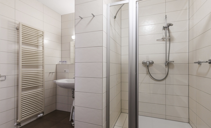 Badezimmer mit Duschkabine, Waschbecken und Handtuchheizkörper.