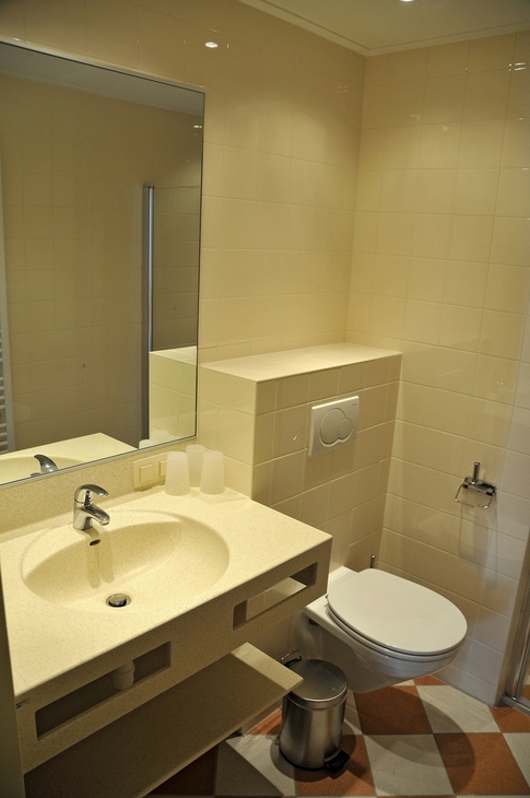 Modernes Badezimmer mit Waschbecken, Spiegel und Toilette.