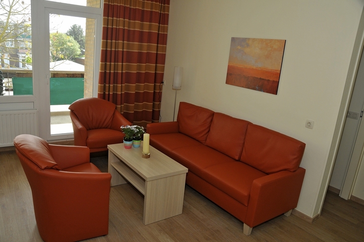 Wohnzimmer mit orangenen Sofas, Tisch und Bild an der Wand.