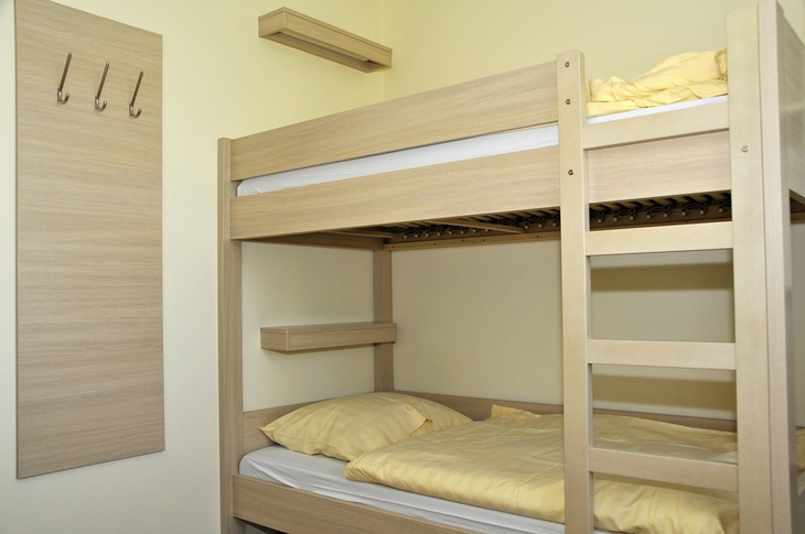 Stapelbett mit gelber Bettwäsche in einem einfachen Zimmer.