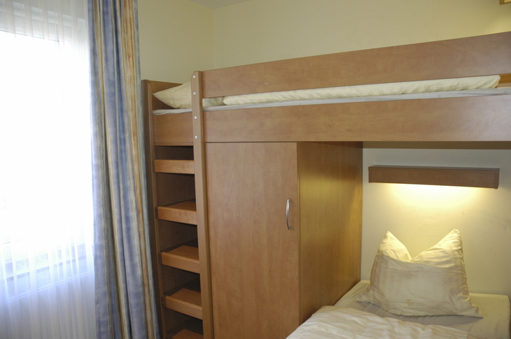 Etagenbett und Fenster in einem Zimmer mit Holzmöbeln.