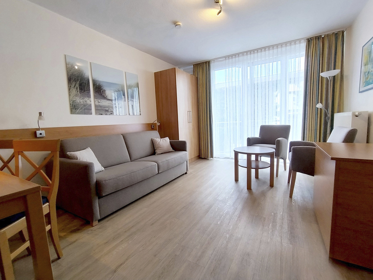 Modernes Wohnzimmer mit Sofa, Tisch, Stühlen und großem Fenster.