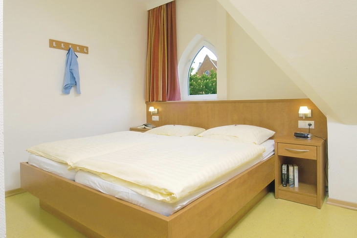 Schlafzimmer mit Doppelbett und Nachttischlampen in einer Ferienanlage.
