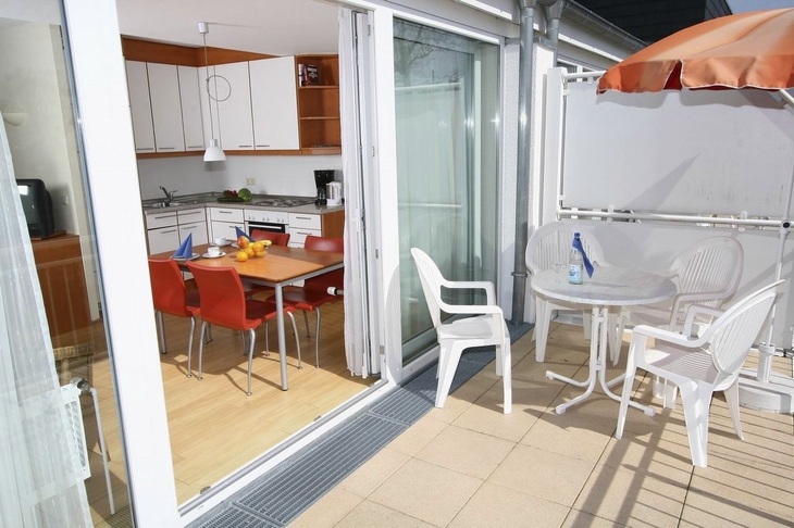 Blick von einer Terrasse in eine moderne Küche mit Esstisch und Stühlen.