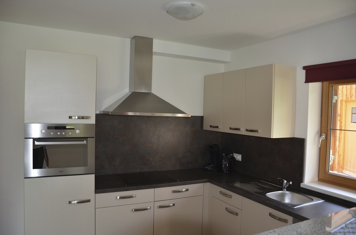 Moderne Küche mit Eckspüle, Ofen und Schränken in einer Ferienwohnung.