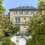Historische Villa mit Gartenansicht, umgeben von blühenden Bäumen.
