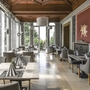 Elegantes Restaurant in der Villa Alwind, in der Ferienanlage Lindau, mit eingedeckten Tischen, grauen gepolsterten Stühlen und großen weißen Fenstern, sowie kunstvoller Holzdecke.