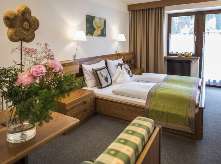 Gemütliches Hotelzimmer mit Doppelbett und Blumenarrangement.
