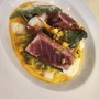 Gourmet-Gericht mit gebratenem Fisch und Gemüse auf weißem Teller.