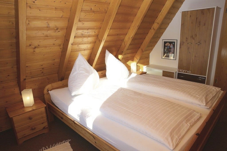 Holzvertäfeltes Schlafzimmer mit Doppelbett und Nachttischlampen.
