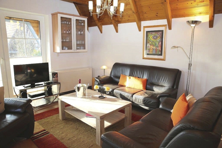 Wohnzimmer mit Ledersofas, Couchtisch, Fernseher und Kunst an der Wand.