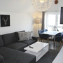 Wohnzimmer mit grauem Sofa, Esstisch, Stühlen und Wandbild eines Hirsches.