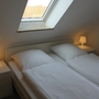 Doppelbett in gemütlichem Schlafzimmer mit Dachfenster und Nachttischen.