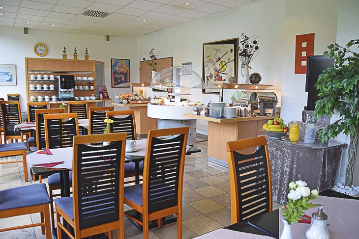 Frühstücksraum im Econtel Hotel München mit gedeckten Tischen und Buffet.