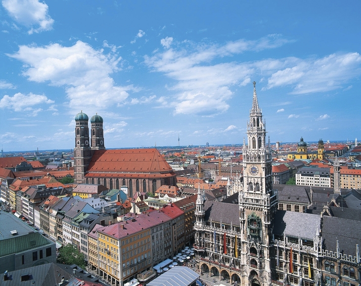 Blick auf München mit Frauenkirche und Neuem Rathaus bei blauem Himmel.