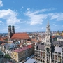 Blick auf München mit Frauenkirche und Neuem Rathaus bei blauem Himmel.