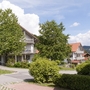 Ferienwohnungen in einer grünen, hügeligen Landschaft mit blauem Himmel und Wolken.
