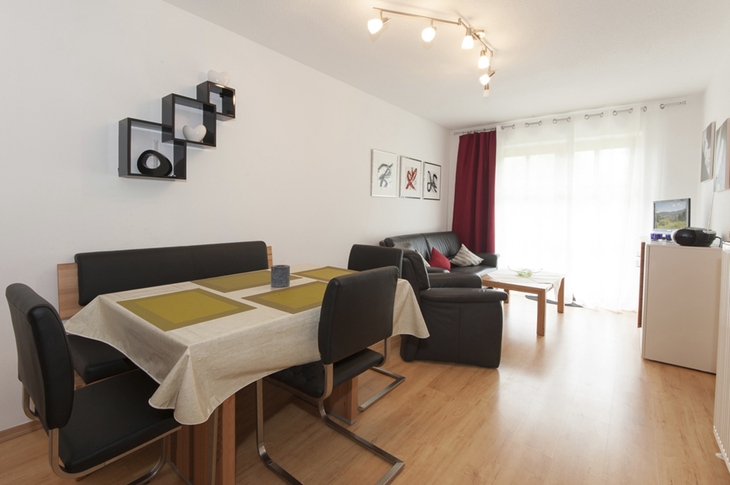 Modern eingerichtetes Wohnzimmer mit Esstisch und Sofa in einer hellen Ferienwohnung.