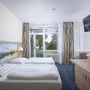 Hotelzimmer mit zwei Betten, Wandbild, Fernseher und Fenster mit Vorhängen.