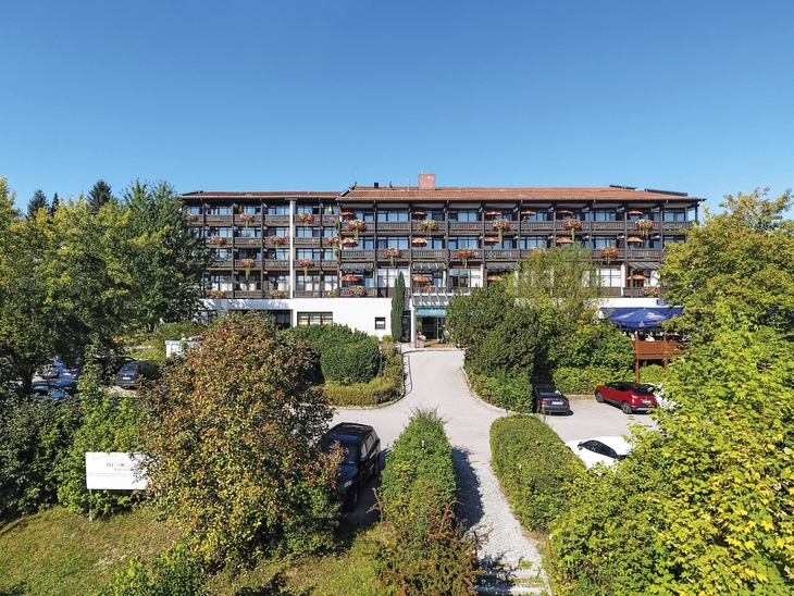 AktiVital Hotel inmitten von Bäumen mit klarem Himmel im Hintergrund.