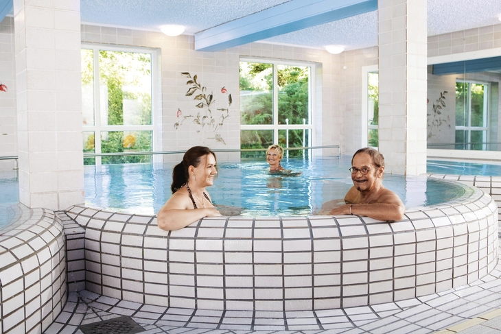 Personen entspannen im Innenpool eines Thermalbads.
