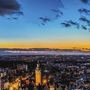 Stadtpanorama von Leipzig bei Sonnenuntergang mit Wolken und beleuchteten Gebäuden.