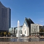 Neues Augusteum Leipzig mit Wasserfontäne im Vordergrund bei klarem Himmel.