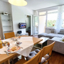 Wohnzimmer einer modernen Ferienwohnung mit Esstisch und gemütlichem Sofa.