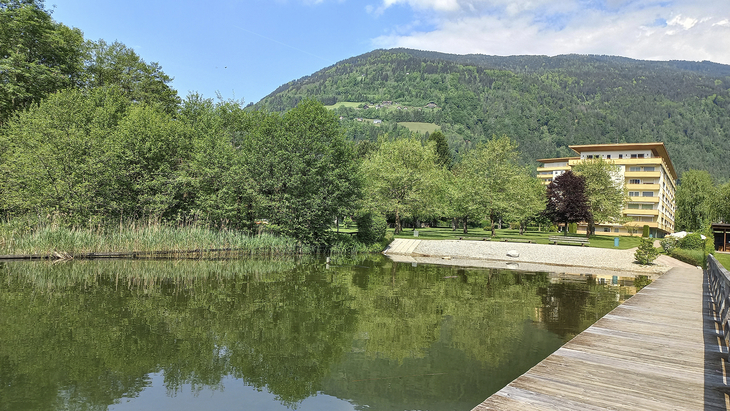 Appartementanlage mit See und bewaldetem Berg im Hintergrund