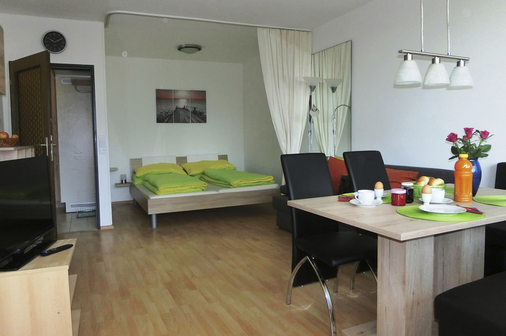 Modernes Appartement mit Doppelbett, Esstisch, Stühlen und heller Einrichtung.