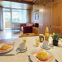 Wohnzimmer mit Esstisch, Brötchen, Getränke, Sofa und Zugang zum Balkon.