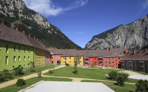 Bunte Gebäude vor Berglandschaft im Erzberg Alpine Resort bei klarem Himmel.
