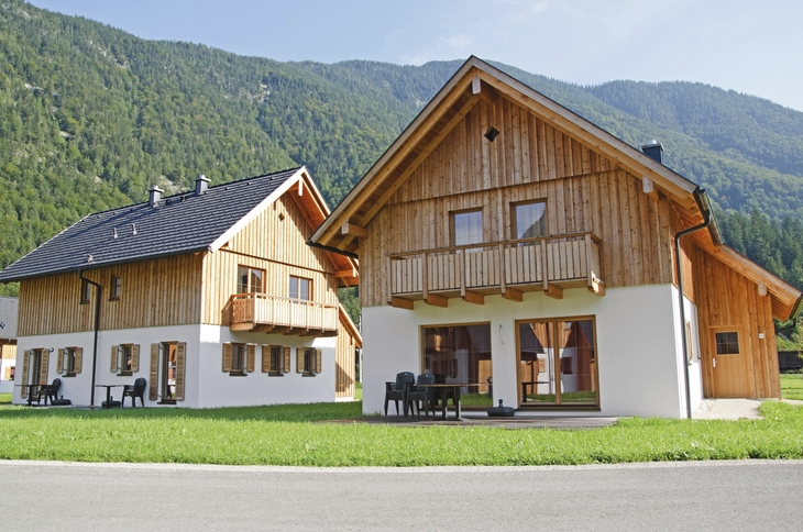 Zwei Holzhäuser vor bewaldetem Berg in Obertraun.
