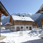 Schneebedeckte Chalets mit Bergen im Hintergrund bei sonnigem Wetter.