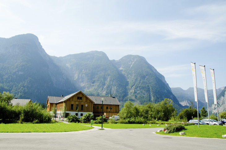 Holzhaus mit Bergkulisse in Obertraun bei klarem Himmel.
