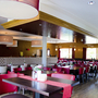 Restaurant mit roten Stühlen und eingedeckten Tischen.