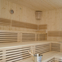 Leere Sauna mit Holzbänken und Eimer.