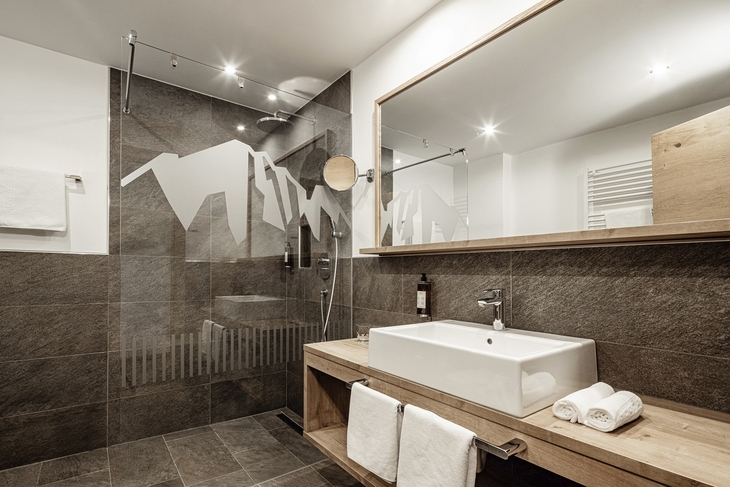 Modernes Badezimmer mit großer Dusche und Holzwaschtisch.