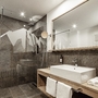 Modernes Badezimmer mit großer Dusche und Holzwaschtisch.