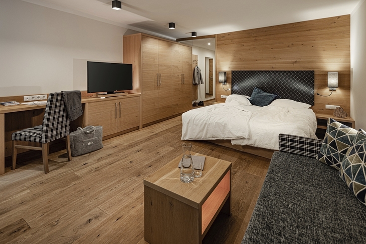 Familiensuite mit Holzmöbeln, Doppelbett, Sofa, Schreibtisch und TV in warmen Tönen.