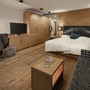 Familiensuite mit Holzmöbeln, Doppelbett, Sofa, Schreibtisch und TV in warmen Tönen.
