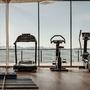 Innenraum eines Fitnessstudios mit Trainingsgeräten vor Panoramafenster.
