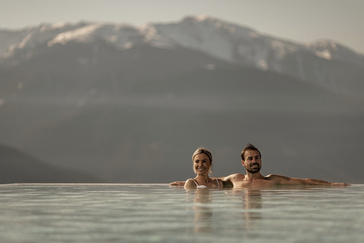 Zwei Personen im Infinity-Pool mit Bergblick in Südtirol.