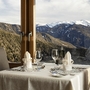 Gedeckter Tisch mit Bergblick durch großes Fenster.