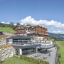 Panoramahotel in alpiner Landschaft mit moderner Architektur und grünen Wiesen.